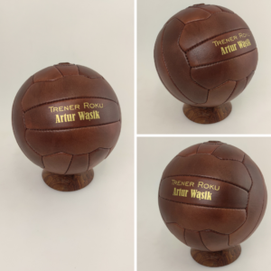 Trzy piłki skórzane z napisem trener roku, na podstawce